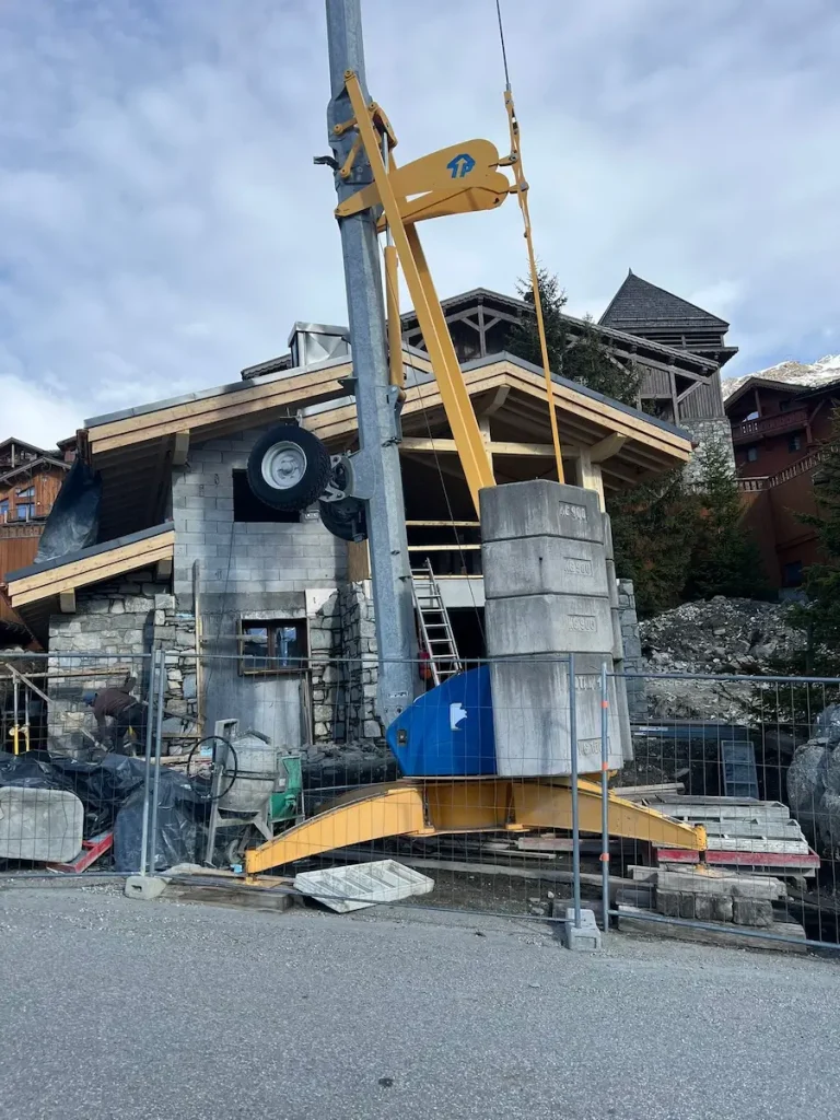 Construction crane lifting materials beside the chalet roofline