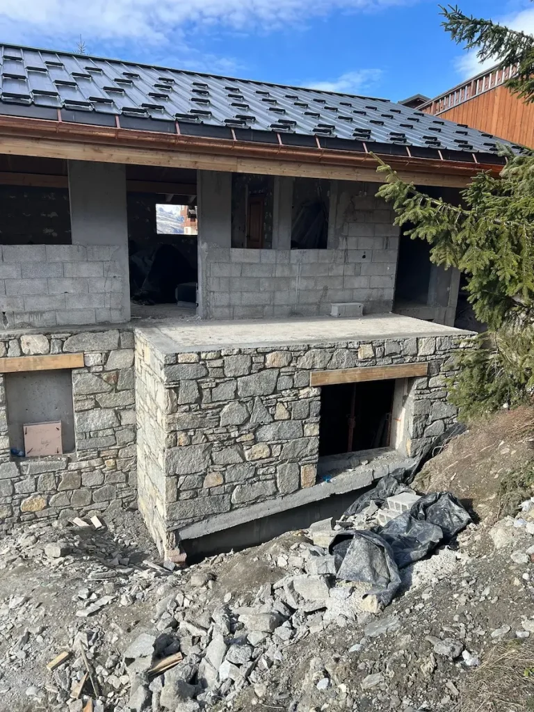Partly renovated chalet exterior with stonework and open wall sections