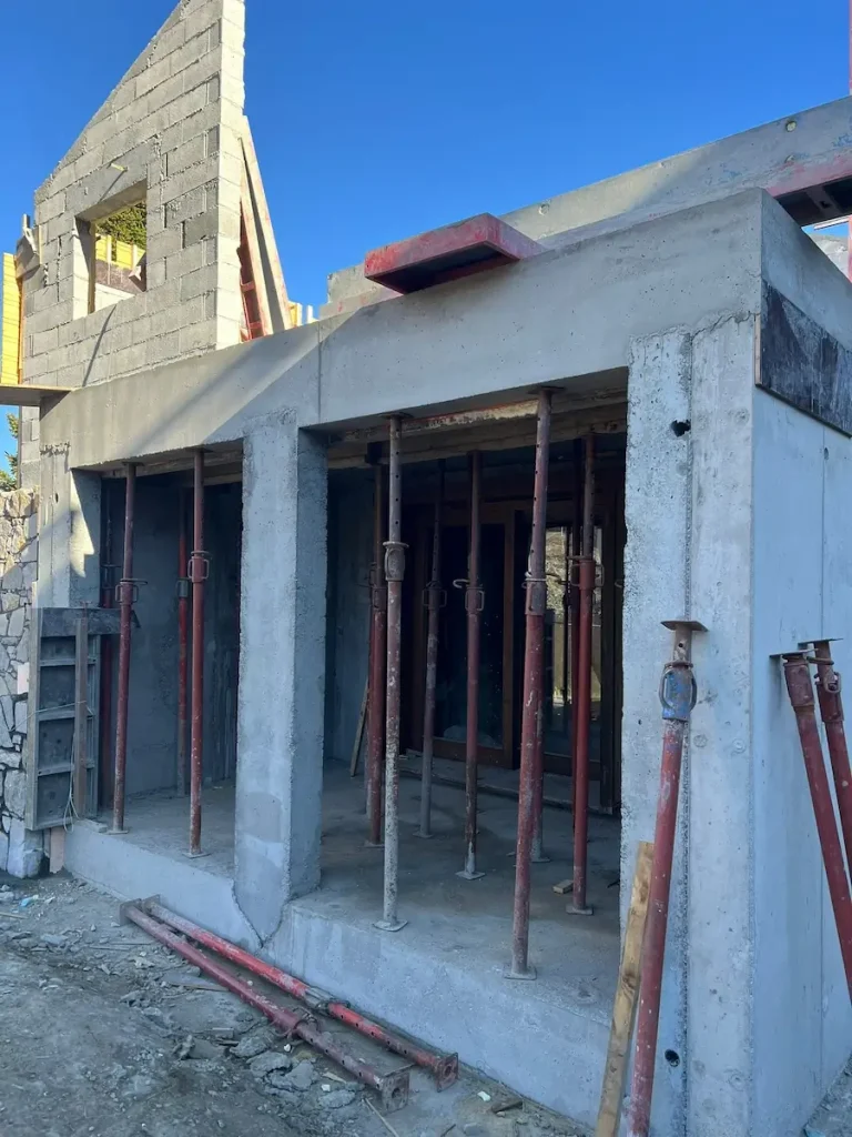 Concrete chalet extension under construction with open bays and support props