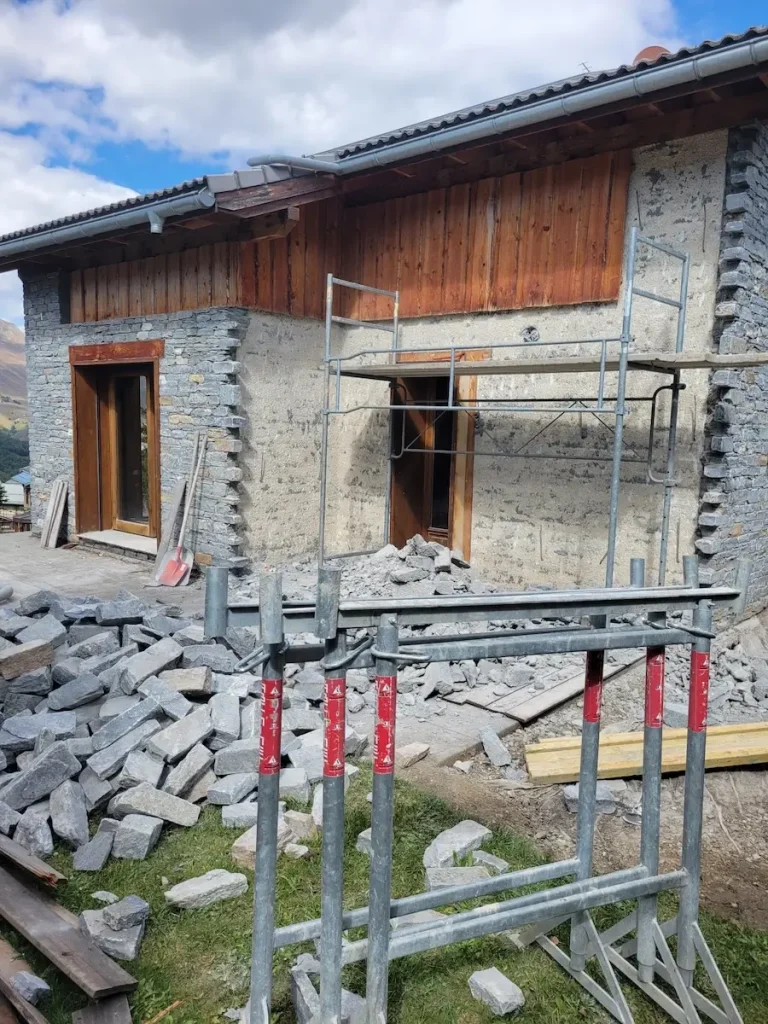 Chalet façade renovation with scaffolding and safety barriers